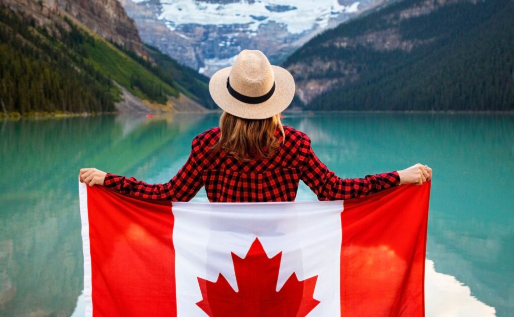 a Canadian traveller in front of a lake with the Canada flag