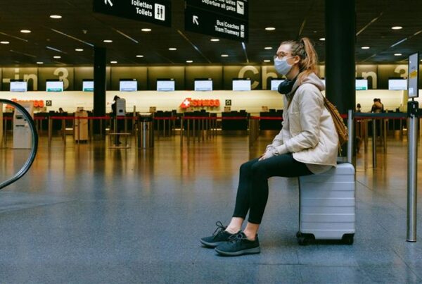 a woman with a face mask waits in airport - crisi management for destinations
